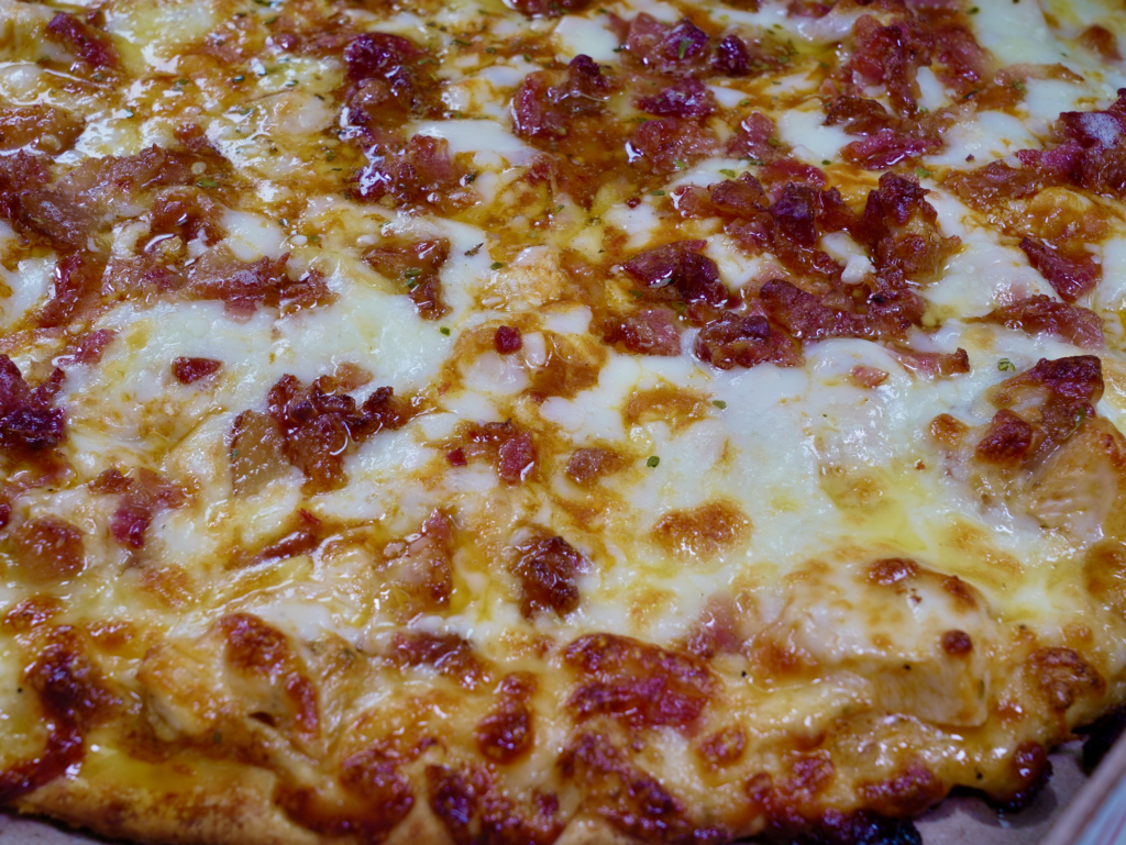 A close up of The Bacon Blaster pizza that is a tomato base pizza with four times the bacon.