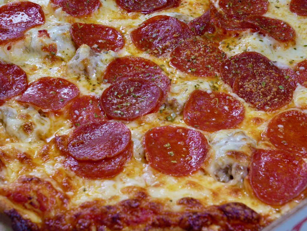 A close up of The Big Cat pizza that is a tomato base pizza with pepperoni & sausage.