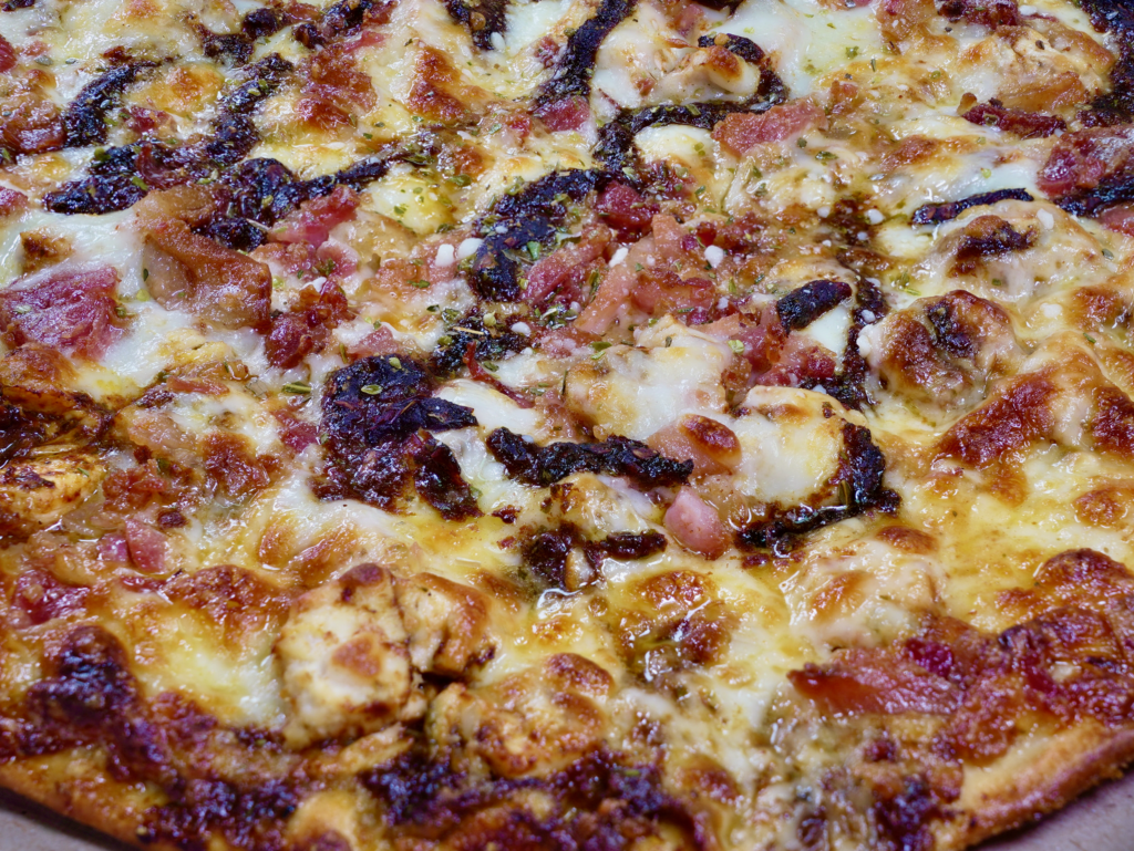 A close up of The Rocket Ship pizza that has thunder punch chicken, bacon, garlic butter ranch base, and thunder punch drizzle.